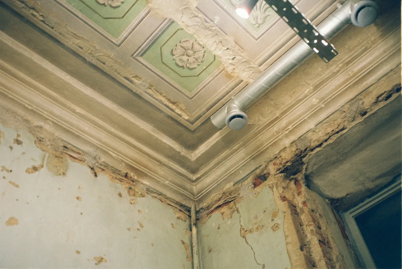 Esquina del techo de una vivienda con manchas de humedad y pintura levantada por una filtración